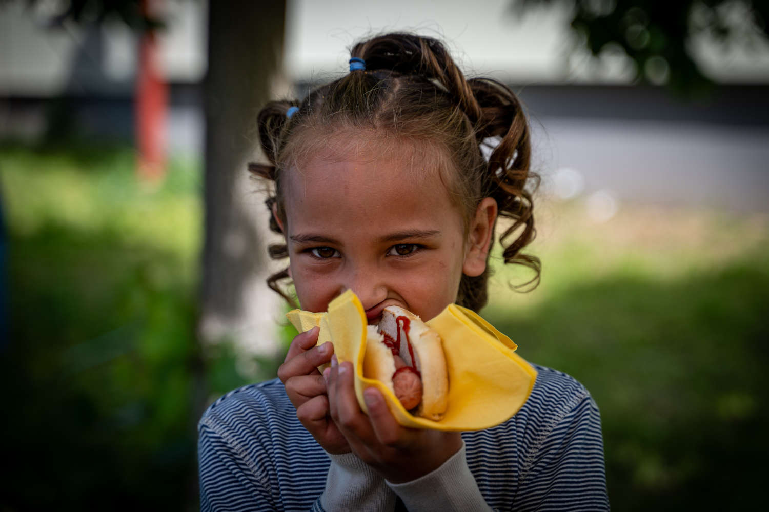 Little girl eating a hot dog outdoors